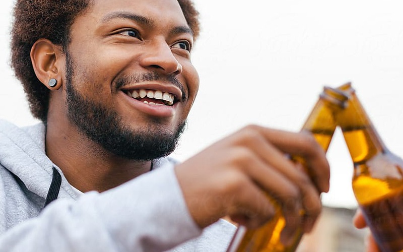 lifestyle image of a man clinking two beer glasses