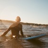 lifestyle image of a human sitting on a surfboard out on the waves
