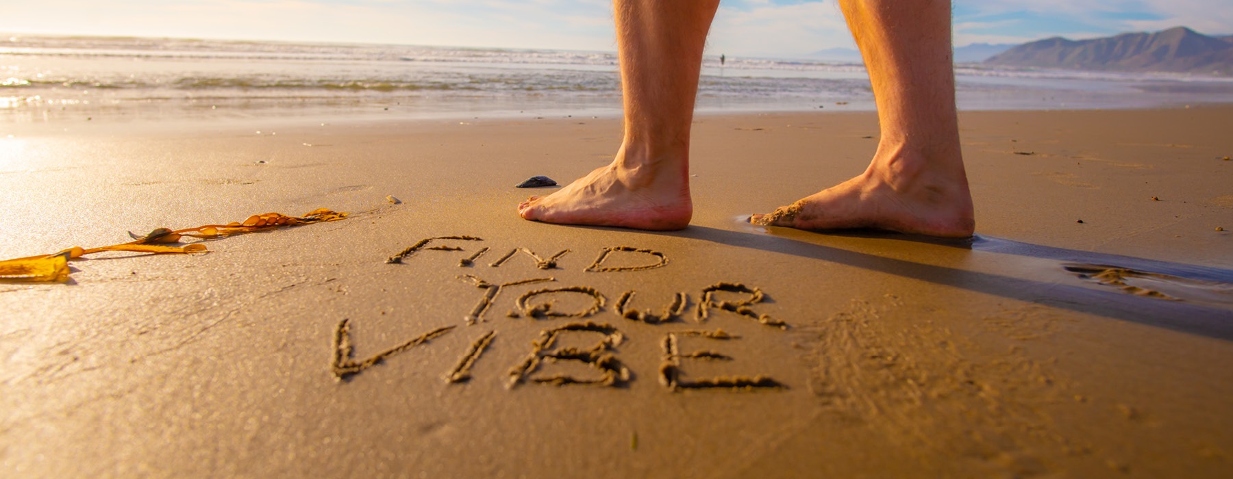 lifestyle image of words written in the sand beside a person's feet